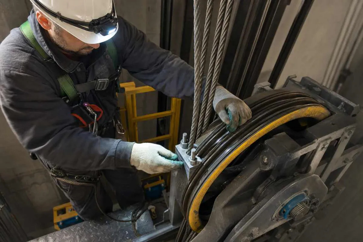 Técnico realizando a troca dos cabos de aço de tração de elevador no Cambuci